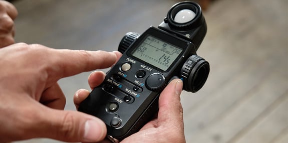 A person holds a spectrometer in their hand and points to the measurement on the screen.