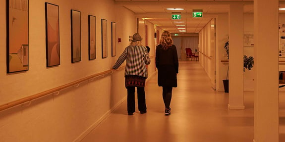 Två kvinnor promenerar och samtalar på en lång korridor omgiven av dygnsrytmljus