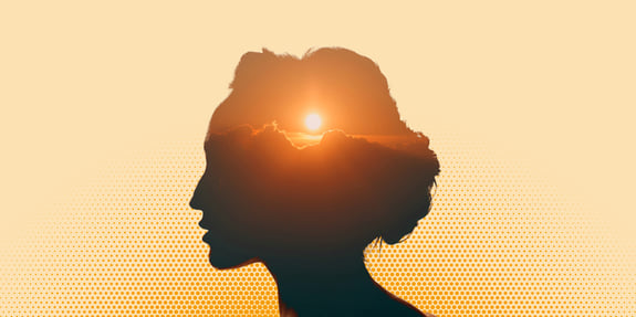 En solnedgång smälter samman med en silhuett av ett kvinnligt ansikte i profil