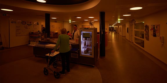 Nurse conversing with a patient at the cafeteria in the hospital unit illuminated with circadian lighting