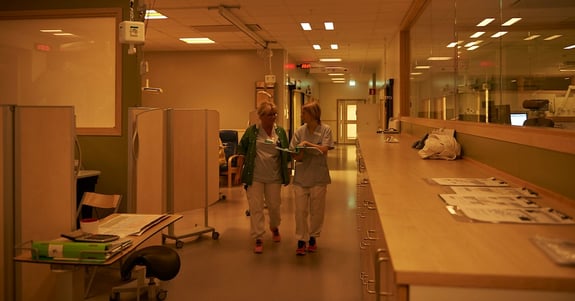 Two nurses walk and talk together in a long hospital corridor in Chroma Zenit circadian lighting at Hudiksvall Hospital