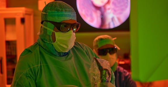 Surgeon looking intensely at a monitor while performing surgery in an operating theatre with ergonomic lighting