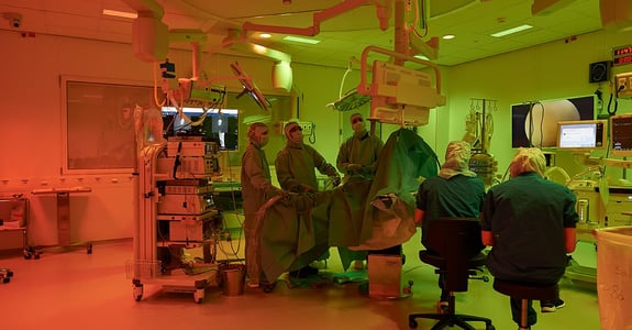 Surgeons standing in an operating theatre performing surgery on a patient in ergonomic lighting