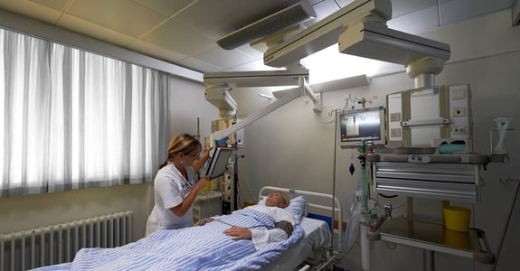 Sygeplejerske snakker med patient på hospitalsstue med døgnrytmelys fra Chromaviso