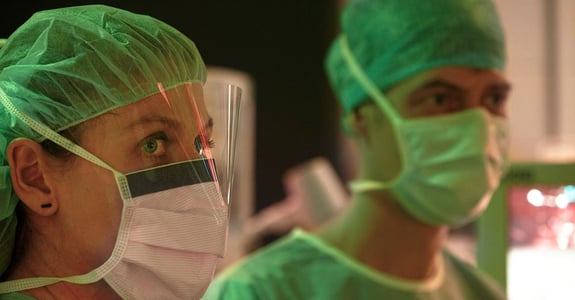 Kirurger tittar på en skärm under operationen medan Chromavisos ergonomiska ljus kan ses i röda och gröna färgtoner