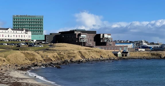 Den nya sjukhustillbyggnaden på Färöarna i soligt väder sett från stranden